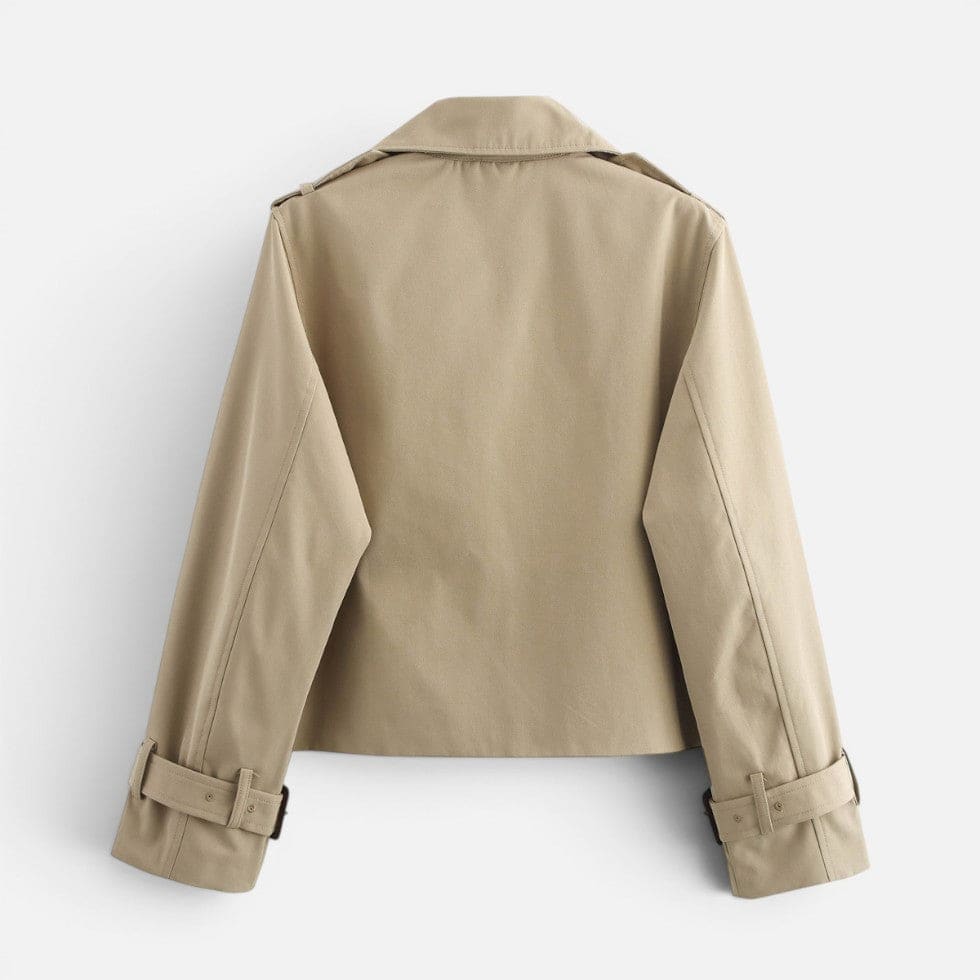 Cropped trench jacket in a neutral tone with double breasted button closure, notched lapel collar, shoulder epaulettes, and belted buckle cuffs displayed flat on a light background._4