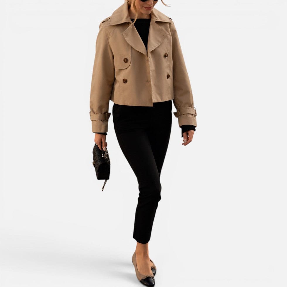Cropped trench jacket in a neutral tone with double breasted button closure, notched lapel collar, shoulder epaulettes, and belted buckle cuffs displayed flat on a light background._6