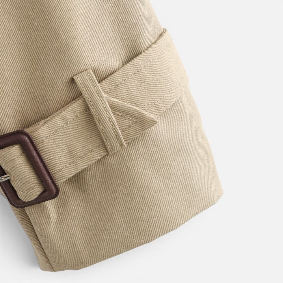 Cropped trench jacket in a neutral tone with double breasted button closure, notched lapel collar, shoulder epaulettes, and belted buckle cuffs displayed flat on a light background._8