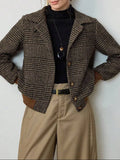 Woman wearing a cropped tweed blazer with houndstooth pattern over a black turtleneck and beige trousers._0