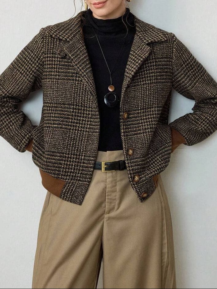 Woman wearing a cropped tweed blazer with houndstooth pattern over a black turtleneck and beige trousers._0