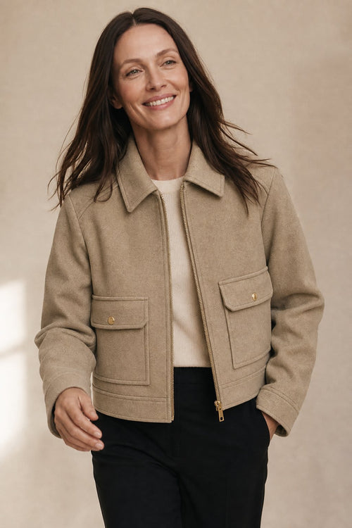 Woman wearing a cropped zip-front jacket with collar and chest pockets, styled over a light sweater and dark pants._0