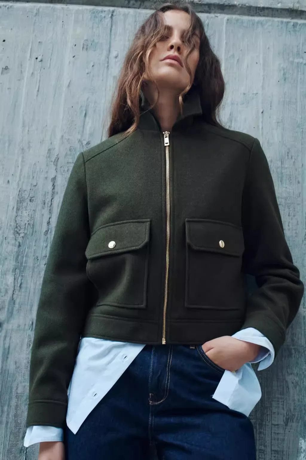 Woman wearing a cropped zip-front jacket with collar and chest pockets, styled over a light sweater and dark pants._12