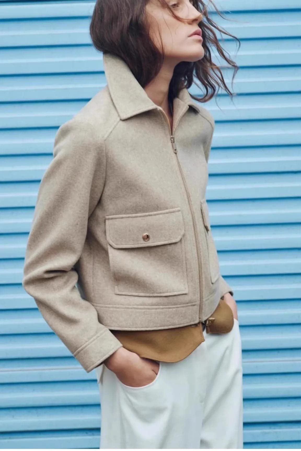 Woman wearing a cropped zip-front jacket with collar and chest pockets, styled over a light sweater and dark pants._13