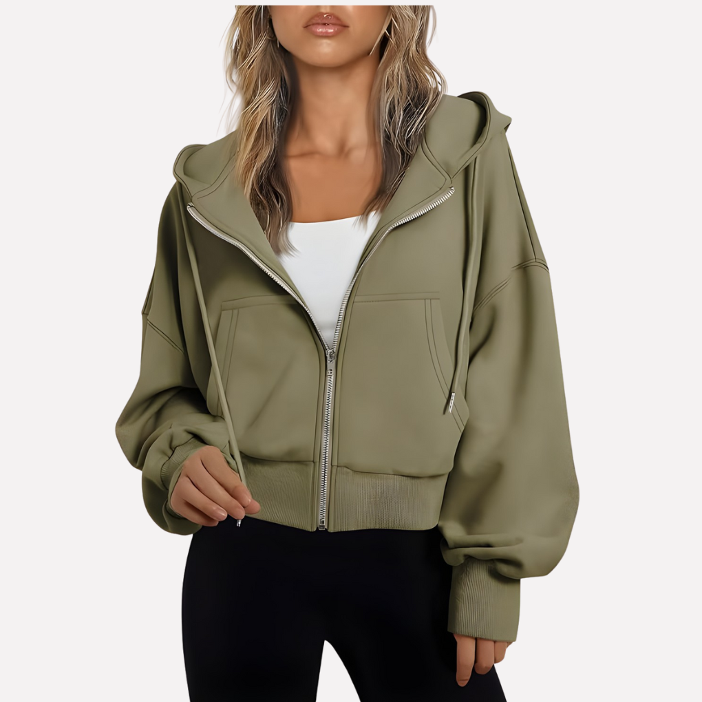 Olive cropped zip-up hoodie with drawstring hood, roomy sleeves, front pockets, and ribbed hem and cuffs, styled over a white top.