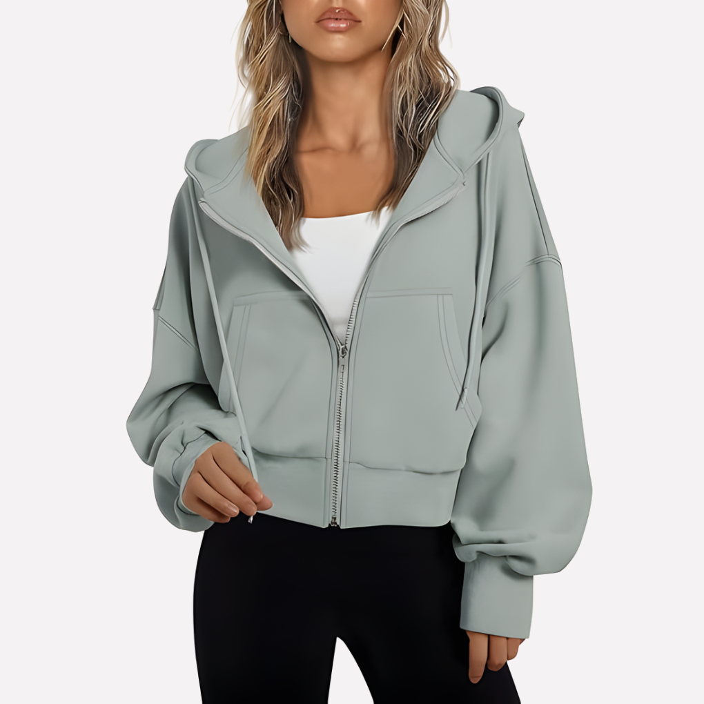 Soft gray cropped hoodie with a drawstring hood, full-length zipper, oversized sleeves, front pockets, and ribbed hem.