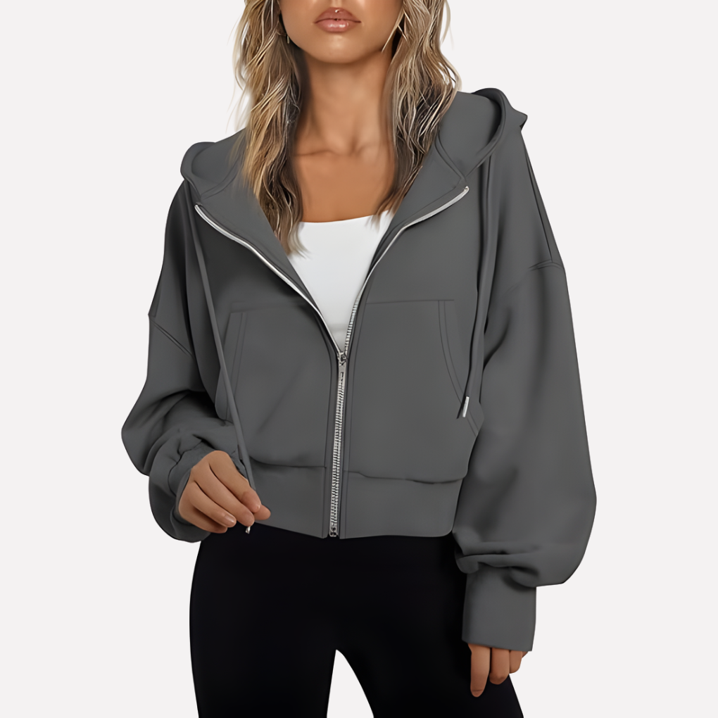 Charcoal gray cropped hoodie shown zipped over a white top, with an adjustable hood, relaxed sleeves, and front pockets.
