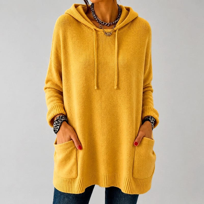 Woman wearing a mustard yellow oversized hooded knit tunic with drawstring hood, ribbed cuffs and two front patch pockets over blue jeans._0