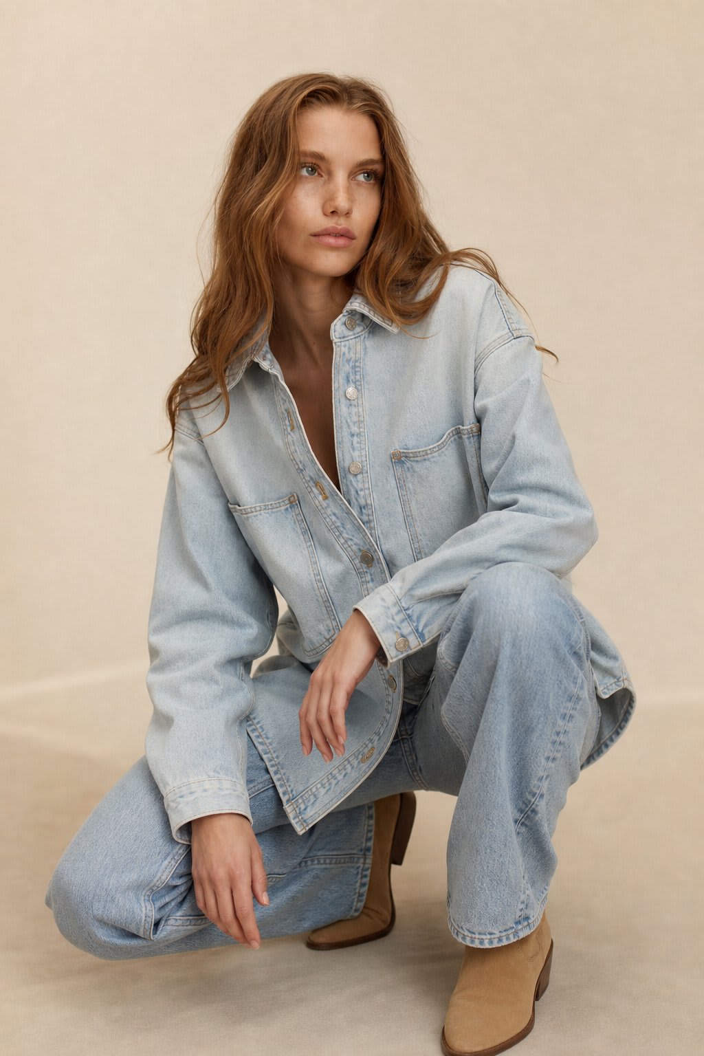 Woman wearing an oversized denim shirt jacket with button front, styled with matching jeans and neutral background._0