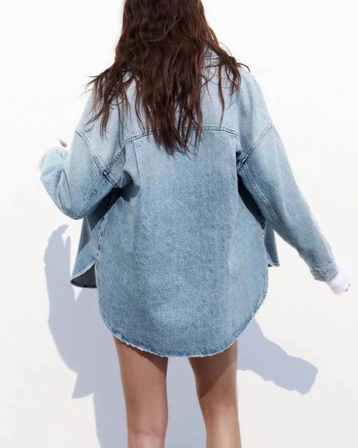 Woman wearing an oversized denim shirt jacket with button front, styled with matching jeans and neutral background._17