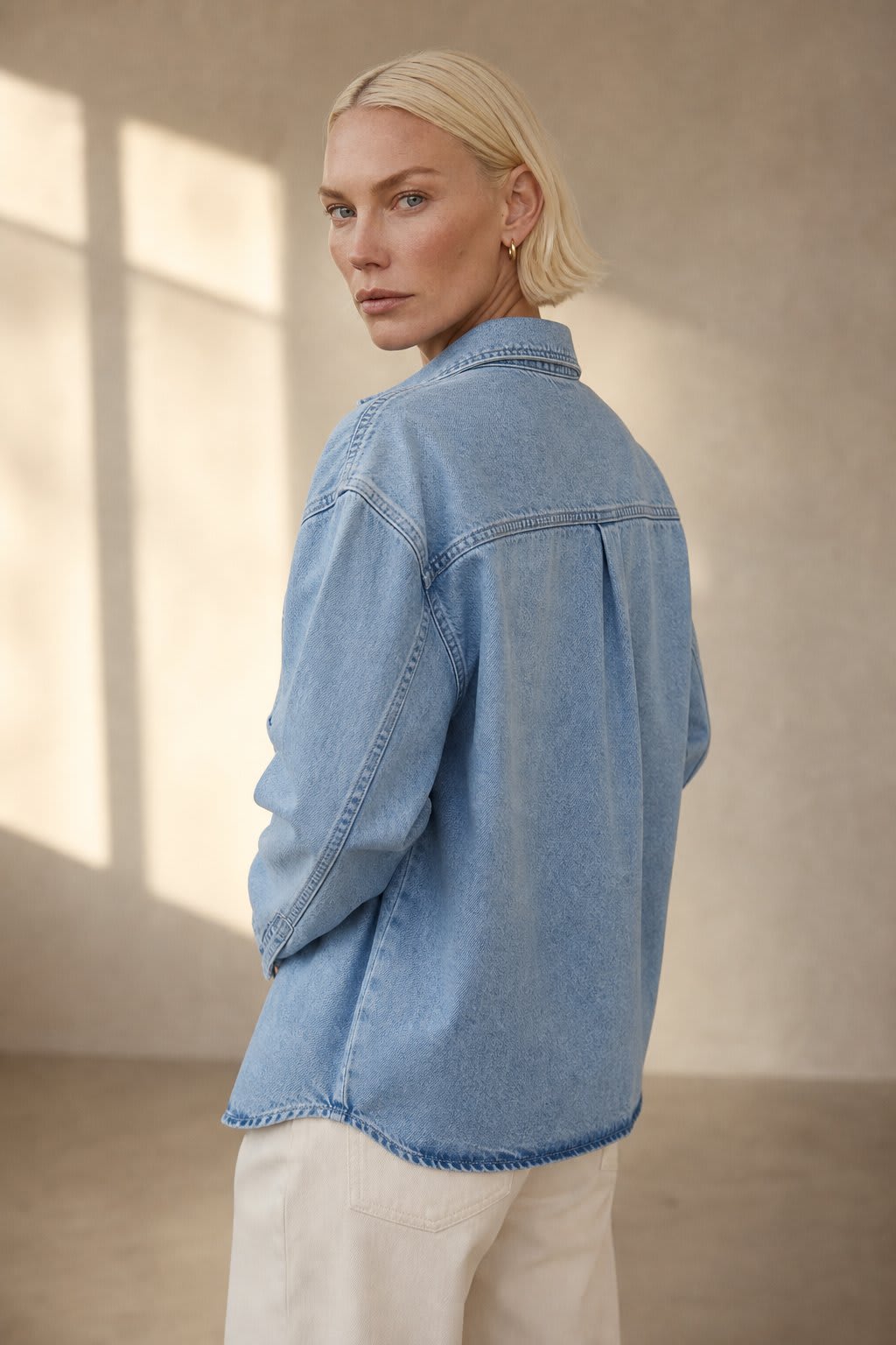 Woman wearing an oversized denim shirt jacket with button front, styled with matching jeans and neutral background._2