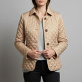 Woman wearing a beige diamond quilted jacket with classic collar and button front closure._0