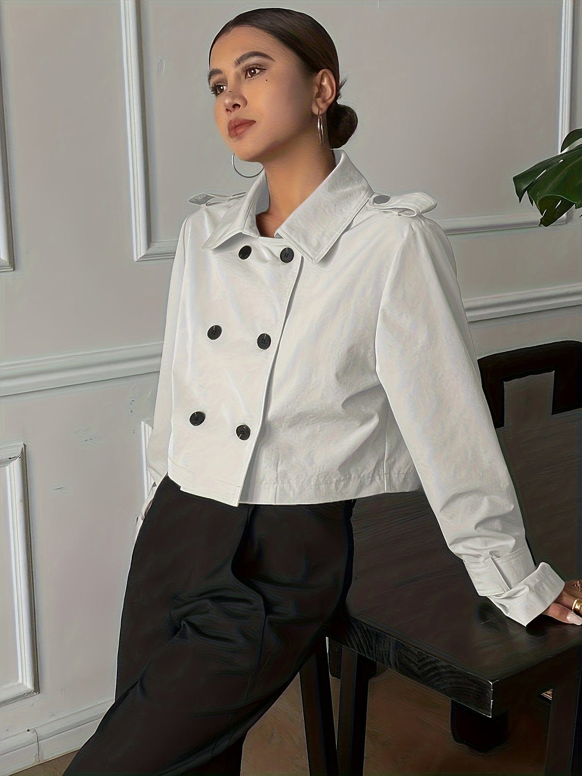 Woman wearing a cropped double-breasted jacket with notch lapel, epaulette shoulder tabs, and buckle cuff sleeves, paired with a white top and dark trousers._1