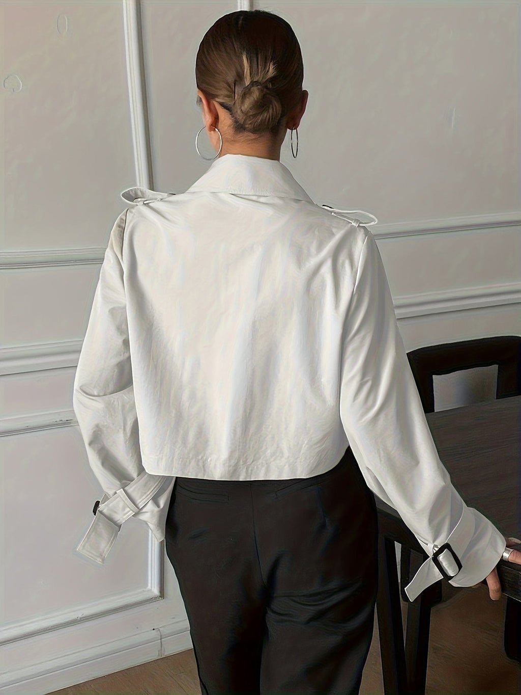 Woman wearing a cropped double-breasted jacket with notch lapel, epaulette shoulder tabs, and buckle cuff sleeves, paired with a white top and dark trousers._2