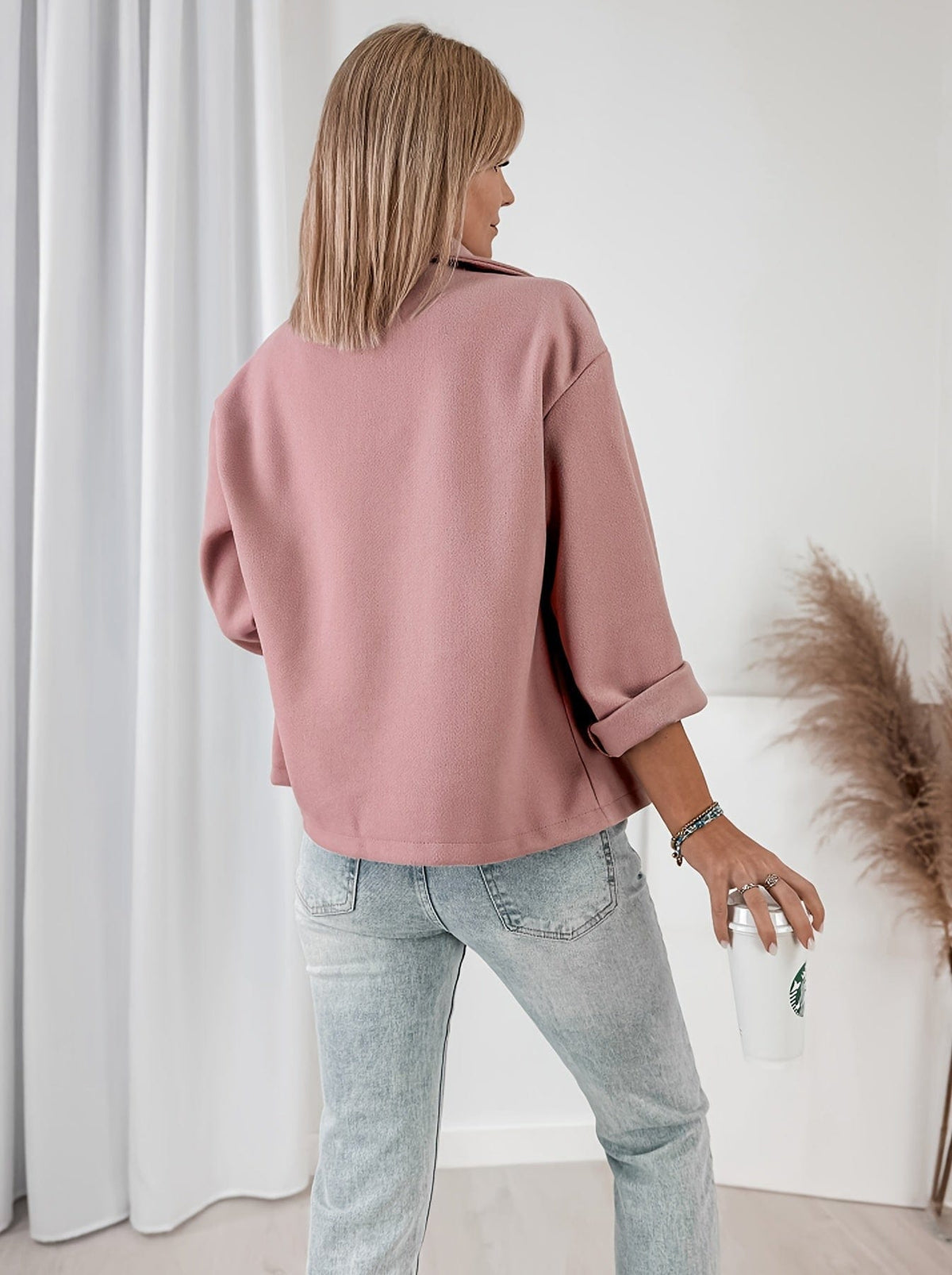 Woman wearing a cropped double breasted pea coat with notched lapel collar and rolled sleeves, styled over a graphic tee and light denim jeans while holding a coffee cup._2