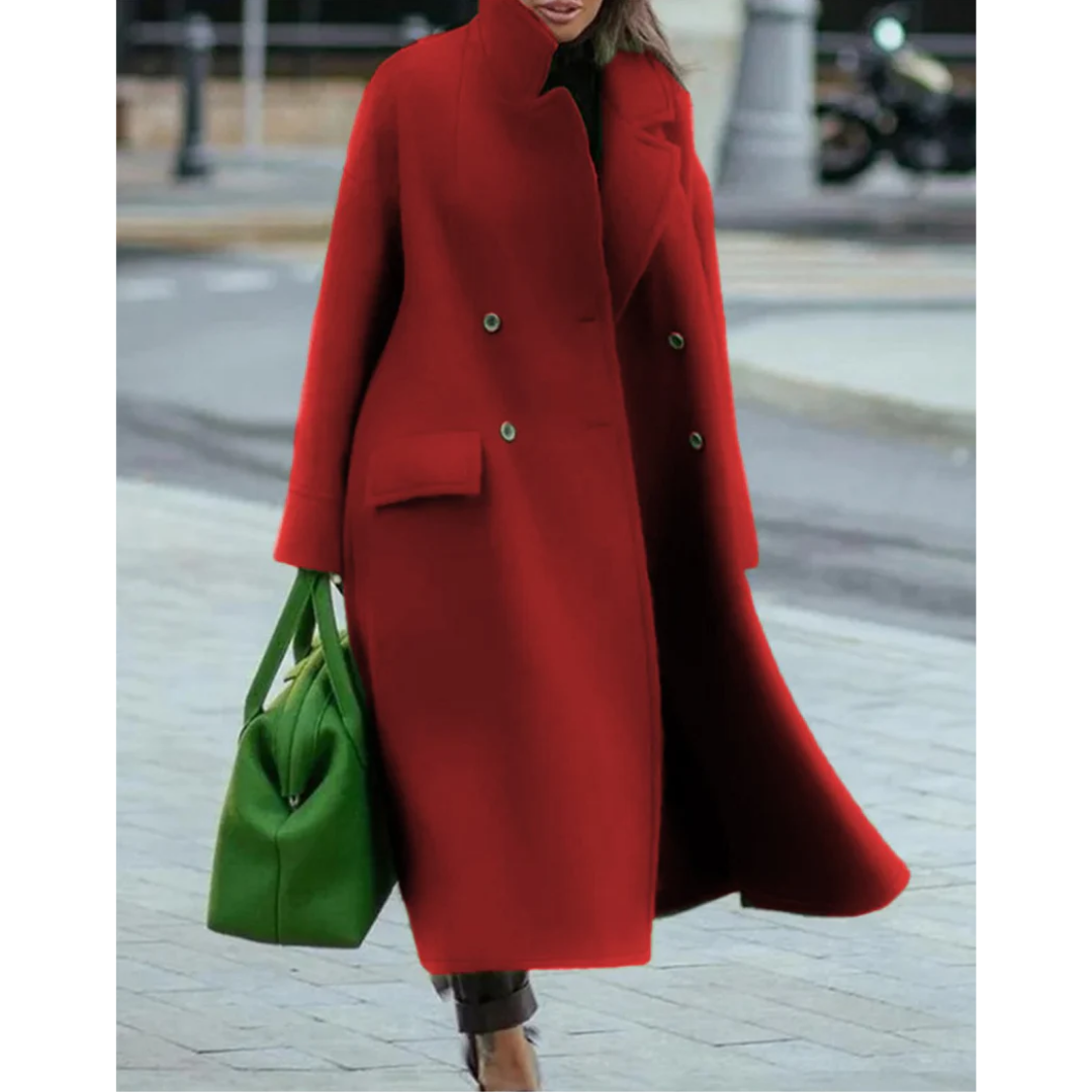 Woman wearing a longline double breasted coat with stand collar and maxi length, holding a green bag, outdoors on a city street._0