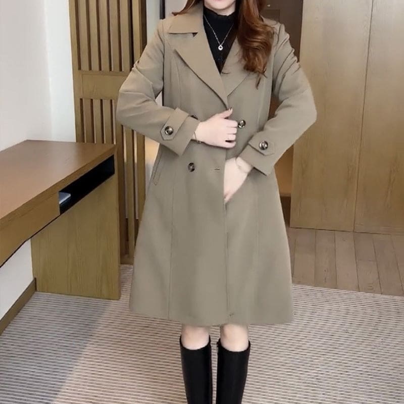 Woman wearing a longline double-breasted trench coat with lapel collar and belted waist in an indoor setting._4