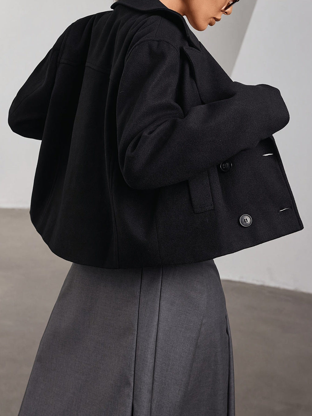 Model wearing a cropped double breasted pea coat with notch lapel and front pockets paired with a pleated mini skirt and sunglasses._1