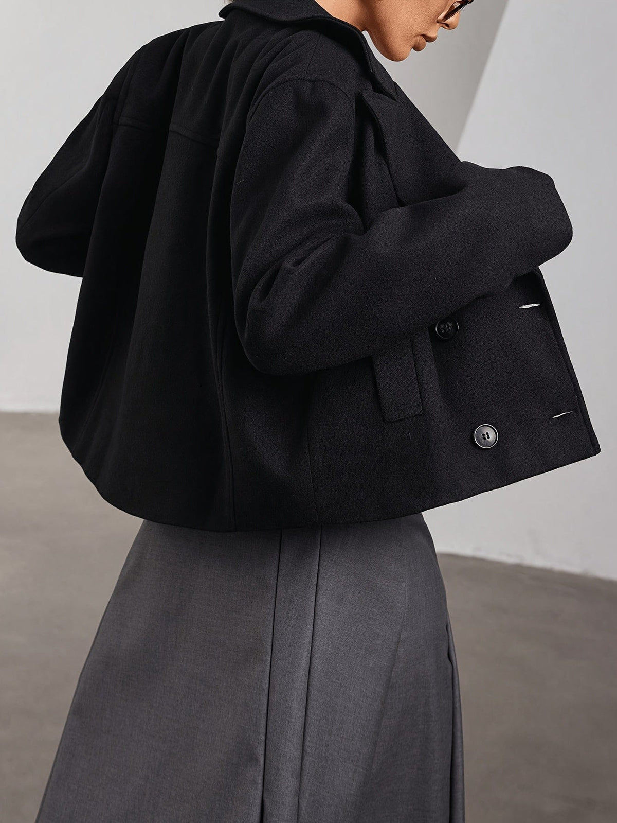 Model wearing a cropped double breasted pea coat with notch lapel and front pockets paired with a pleated mini skirt and sunglasses._1