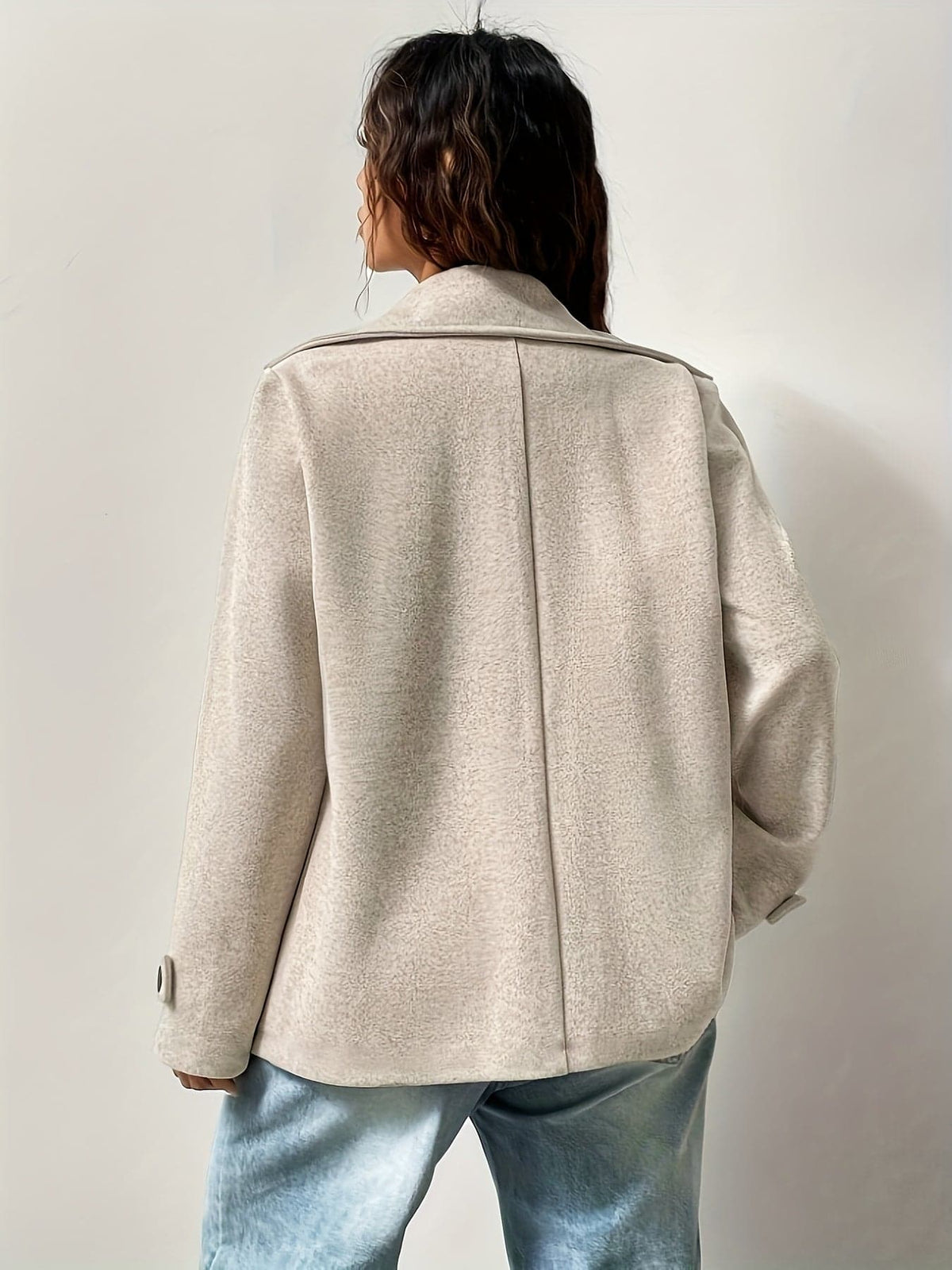 Woman wearing an oversized double-breasted pea coat with notched lapel, white crop top, and light wash jeans against a neutral background._2