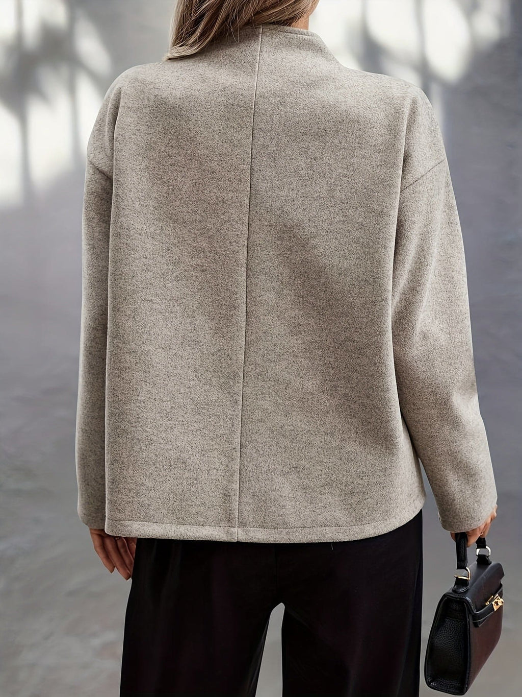 Woman wearing a beige double breasted pea coat with stand collar and oversized silhouette on a city street._1