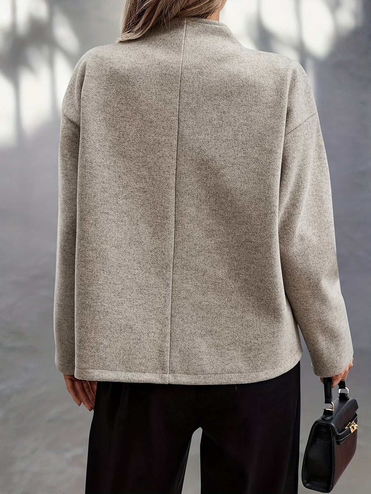 Woman wearing a beige double breasted pea coat with stand collar and oversized silhouette on a city street._1
