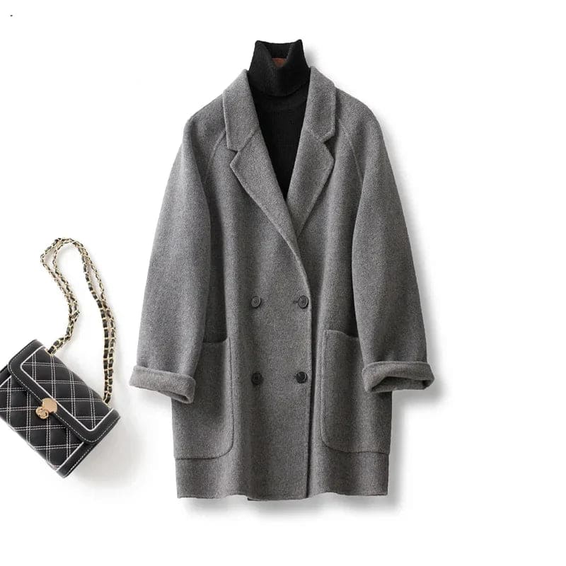 Woman wearing a gray double-breasted coat with rolled cuffs and notched lapels over a black turtleneck_15