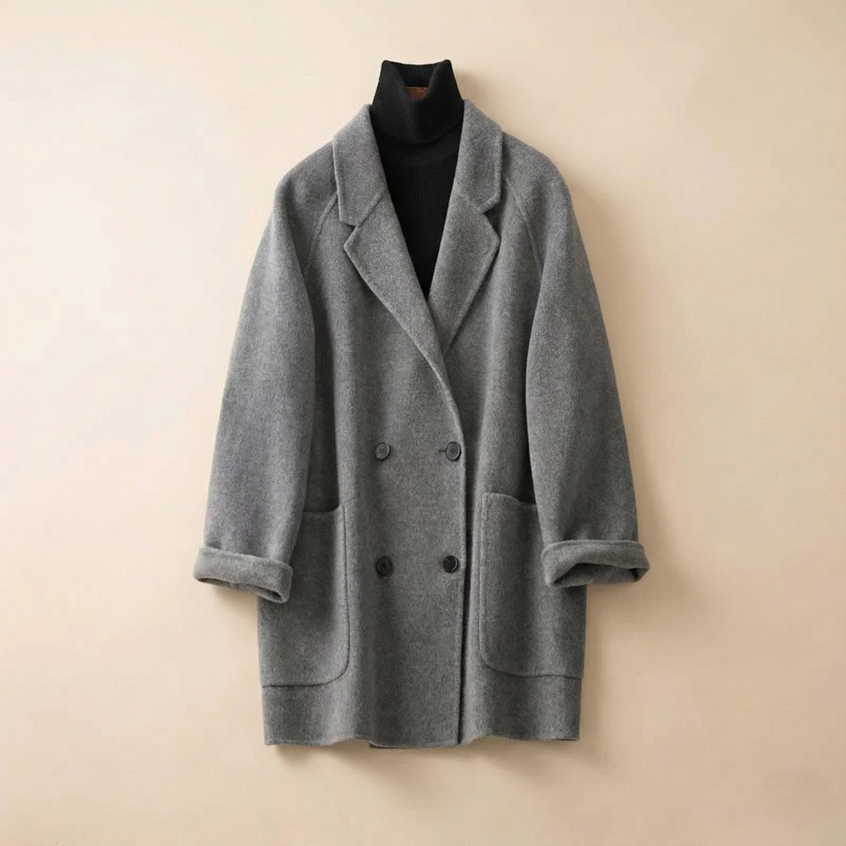 Woman wearing a gray double-breasted coat with rolled cuffs and notched lapels over a black turtleneck_7