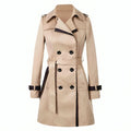 Beige double breasted trench coat with black contrast trim, belted waist, notched collar, and shoulder epaulets displayed on mannequin_0