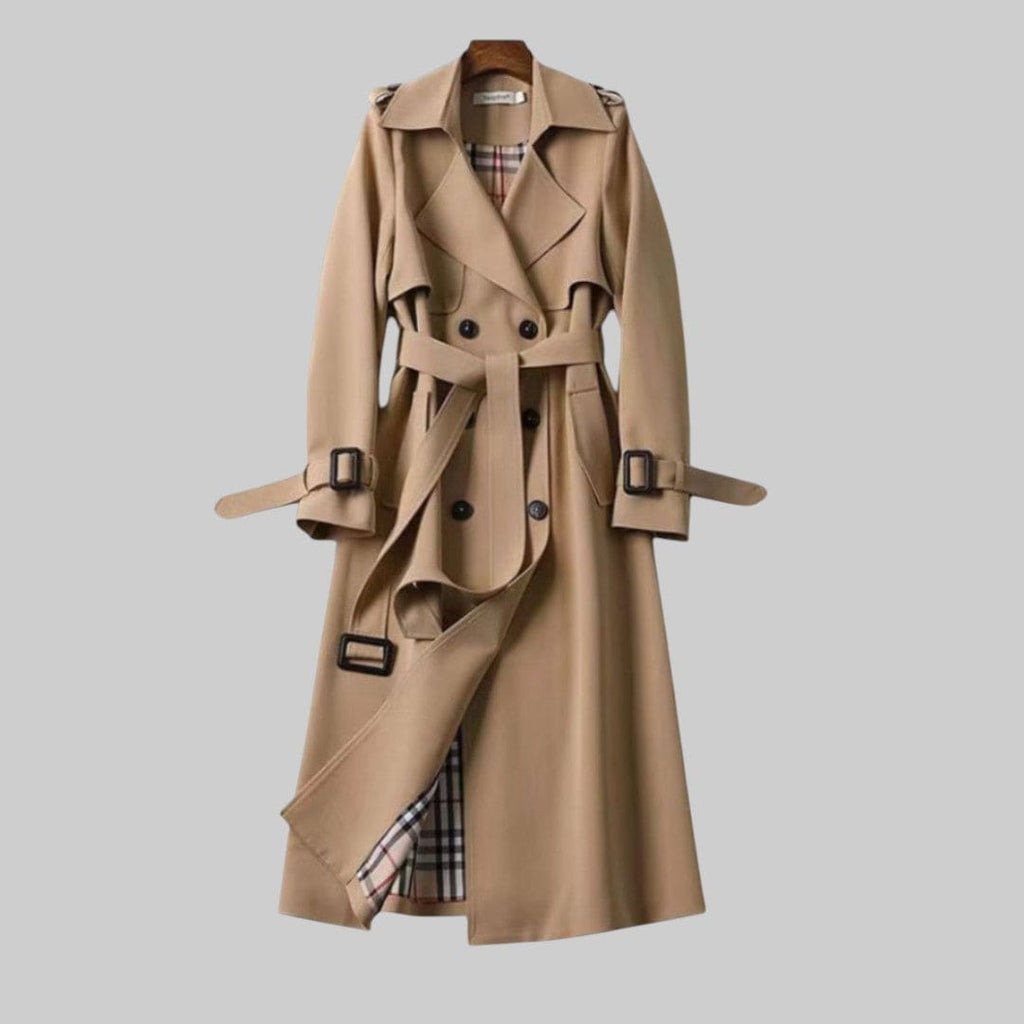 A longline trench coat with double breasted front, belted waist, lapel collar, and adjustable cuff straps displayed on a hanger._0