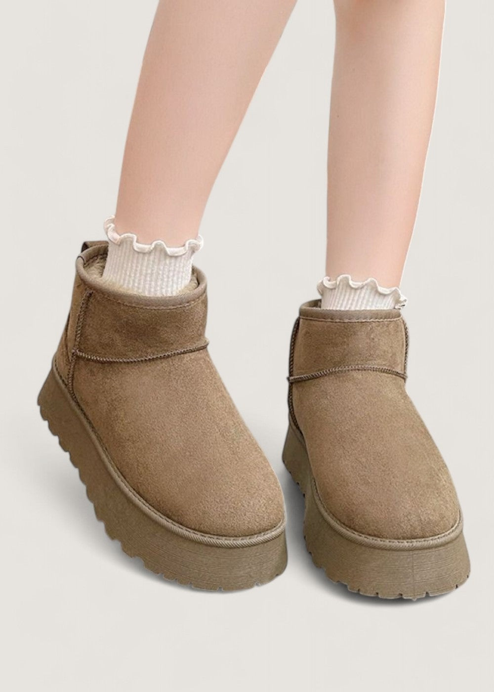 Pair of brown platform ankle boots worn with white ruffle-trim socks, viewed from the front to show their rounded toes.