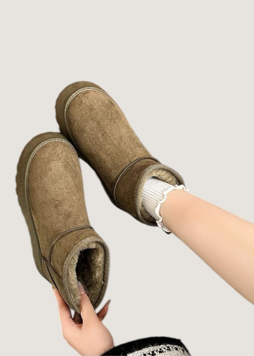 Brown ankle boots held at an angled top view, clearly showing the plush faux fur interiors and platform soles.