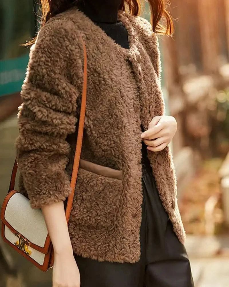 Woman wearing a textured button-front coat with a round neckline over a ribbed turtleneck and matching trousers in a neutral interior setting._12