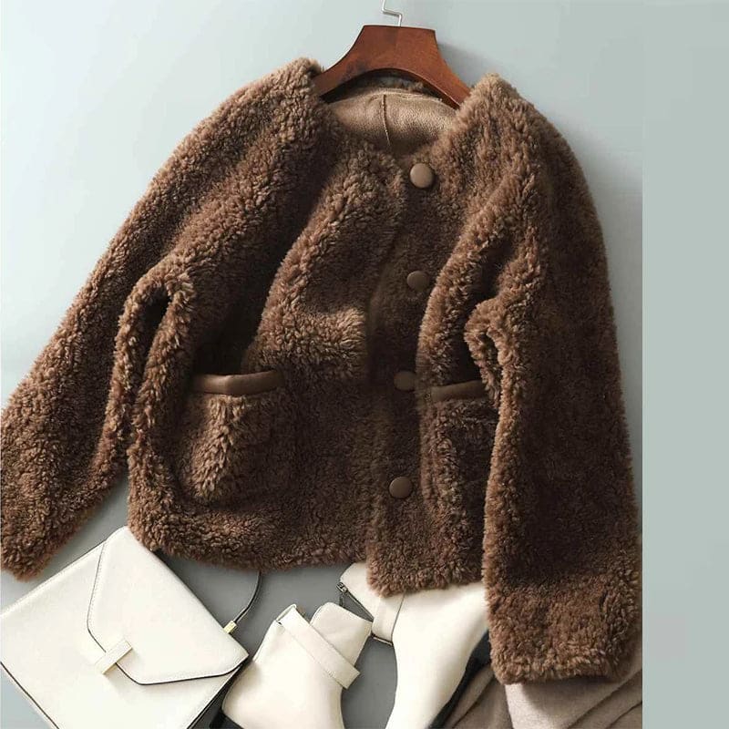 Woman wearing a textured button-front coat with a round neckline over a ribbed turtleneck and matching trousers in a neutral interior setting._13