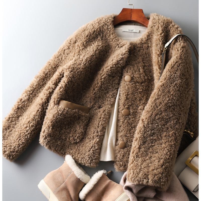 Woman wearing a textured button-front coat with a round neckline over a ribbed turtleneck and matching trousers in a neutral interior setting._14