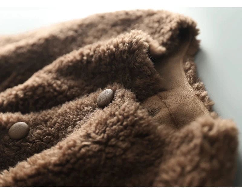 Woman wearing a textured button-front coat with a round neckline over a ribbed turtleneck and matching trousers in a neutral interior setting._17