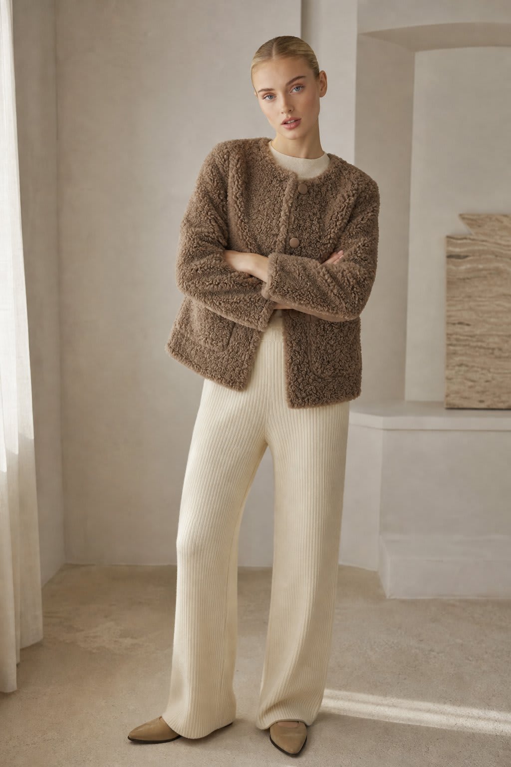 Woman wearing a textured button-front coat with a round neckline over a ribbed turtleneck and matching trousers in a neutral interior setting._4