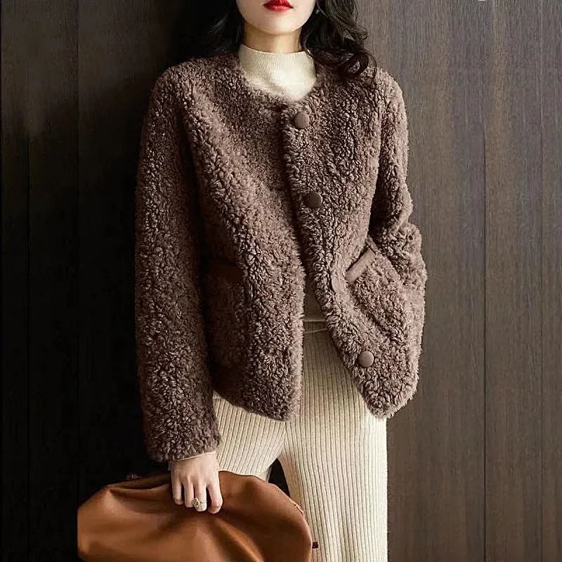Woman wearing a textured button-front coat with a round neckline over a ribbed turtleneck and matching trousers in a neutral interior setting._6