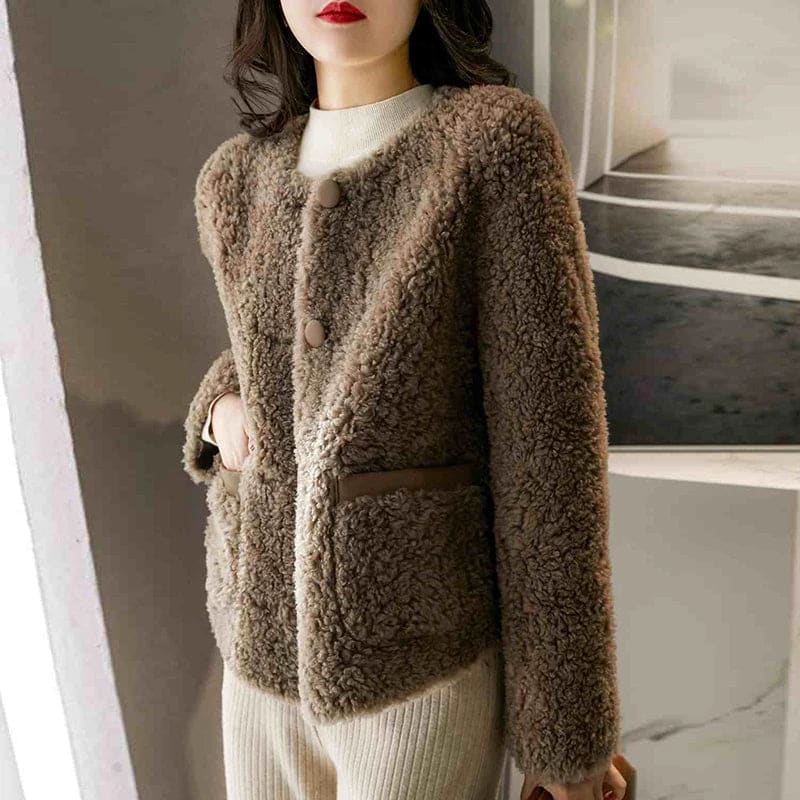 Woman wearing a textured button-front coat with a round neckline over a ribbed turtleneck and matching trousers in a neutral interior setting._7