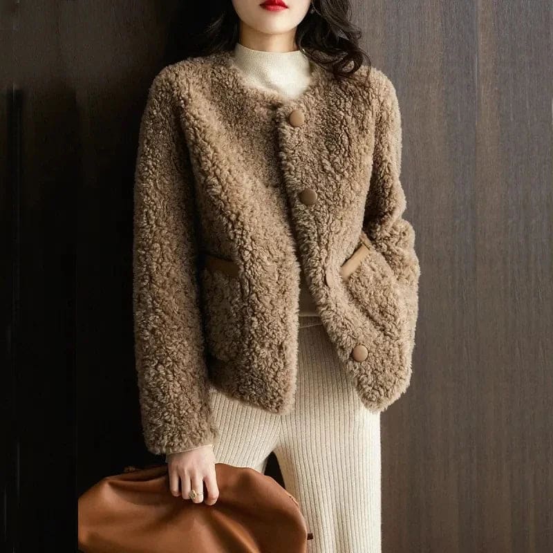 Woman wearing a textured button-front coat with a round neckline over a ribbed turtleneck and matching trousers in a neutral interior setting._8