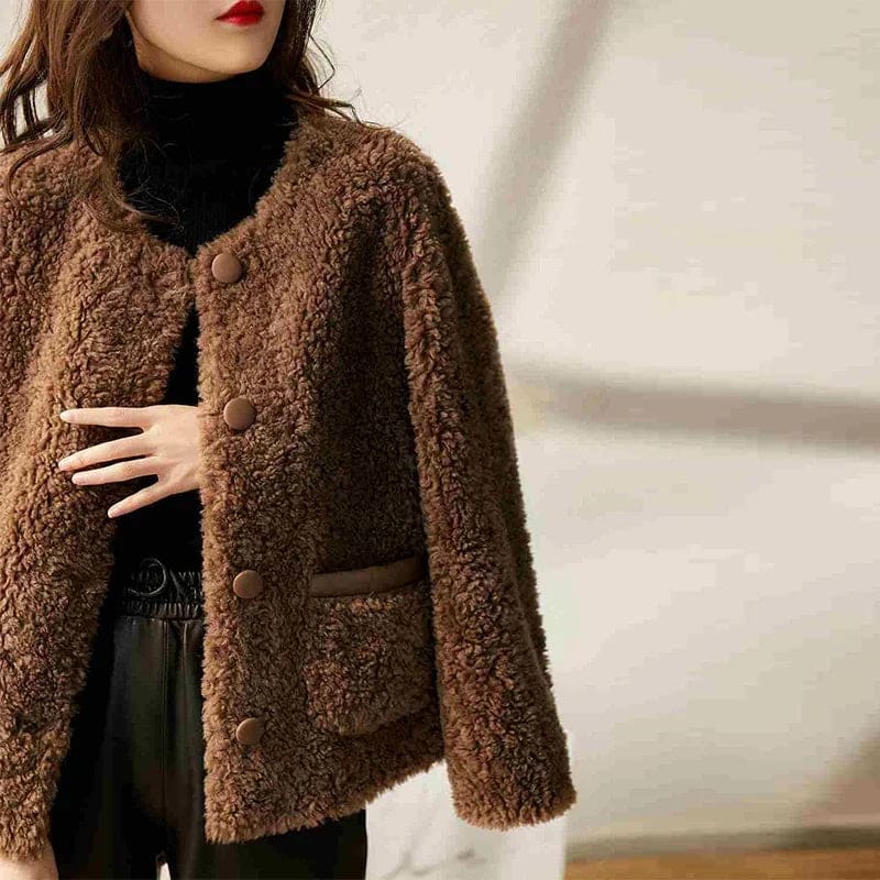 Woman wearing a textured button-front coat with a round neckline over a ribbed turtleneck and matching trousers in a neutral interior setting._9