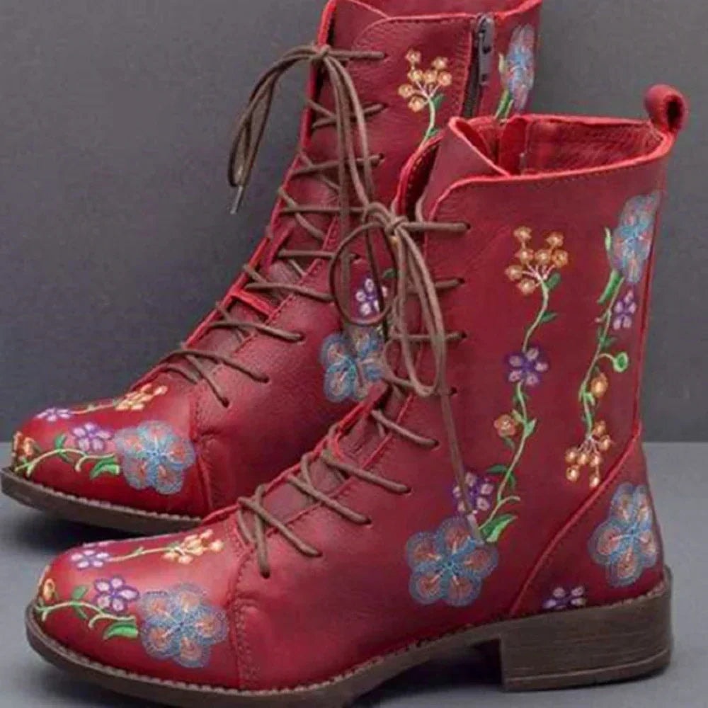 Deep red ankle boots featuring colorful floral embroidery, brown lace-up fronts, side zippers, and low block heels.