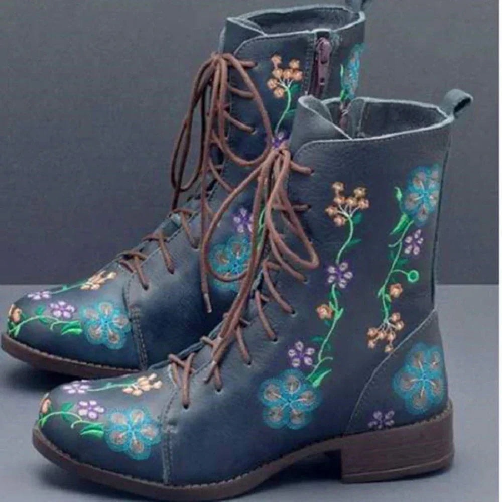 Navy ankle boots decorated with bright embroidered flowers and vines, brown laces, side zippers, and low block heels.