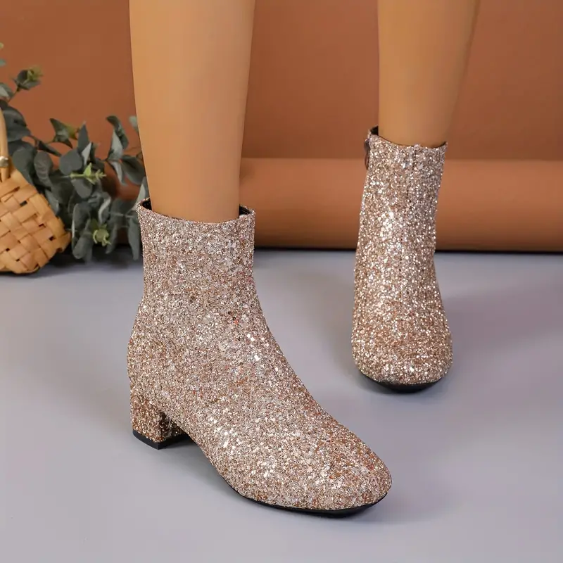 Champagne glitter ankle boots shown from the front, emphasizing the sparkling ankle-height shafts, rounded toes, and low block heels.