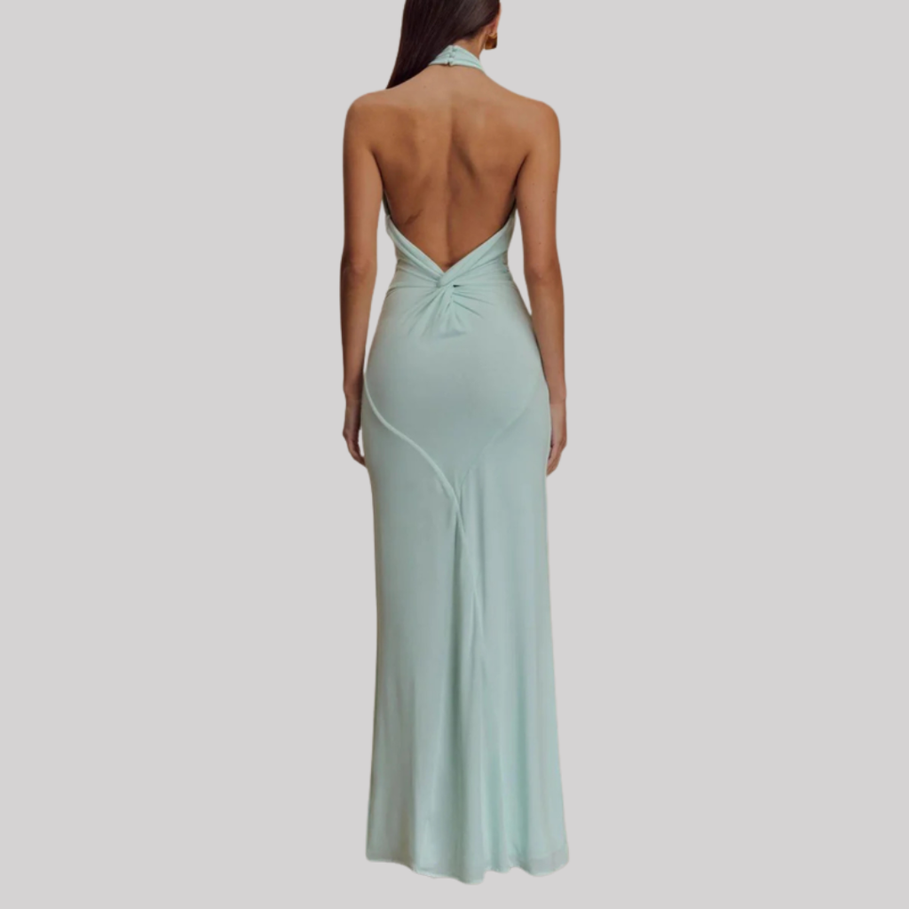 Model wearing a halter neck maxi dress with bodycon fit, open back design, and floor-length hem in a soft pastel shade._1