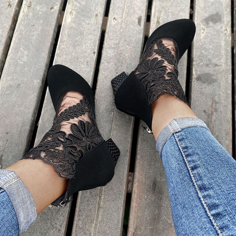 Woman wearing heeled ankle boots featuring sheer floral lace panels, solid toe and heel, and studded block heel detail with cuffed jeans._1