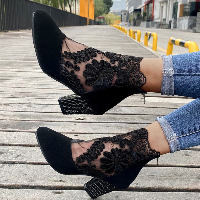 Woman wearing heeled ankle boots featuring sheer floral lace panels, solid toe and heel, and studded block heel detail with cuffed jeans._2