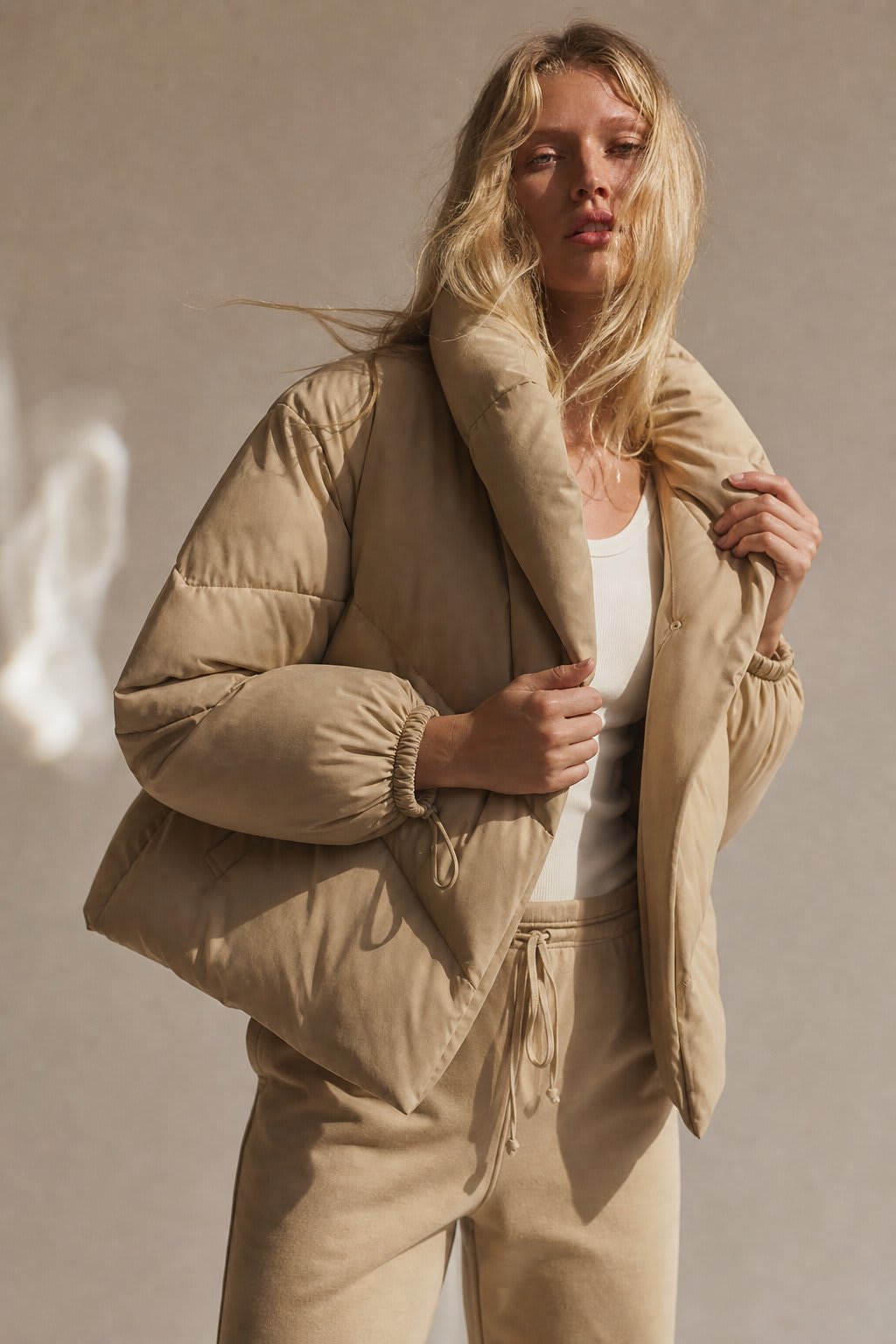 Woman wearing a hooded quilted puffer jacket in a cropped relaxed fit, styled with a light sweater and trousers._2