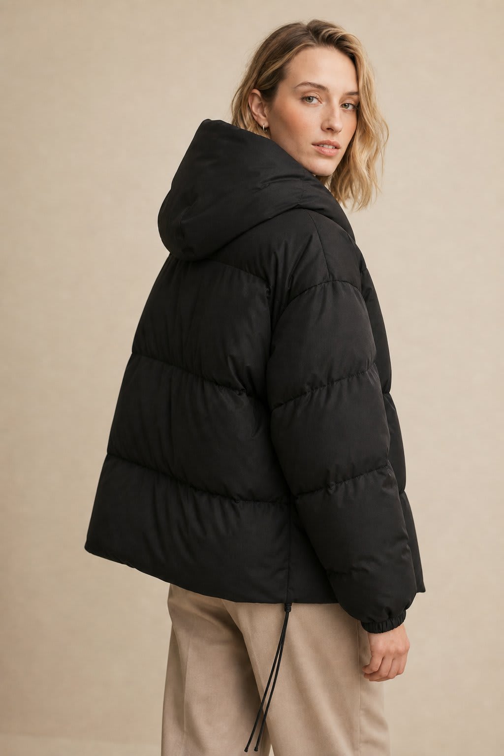 Woman wearing a hooded quilted puffer jacket in a cropped relaxed fit, styled with a light sweater and trousers._4