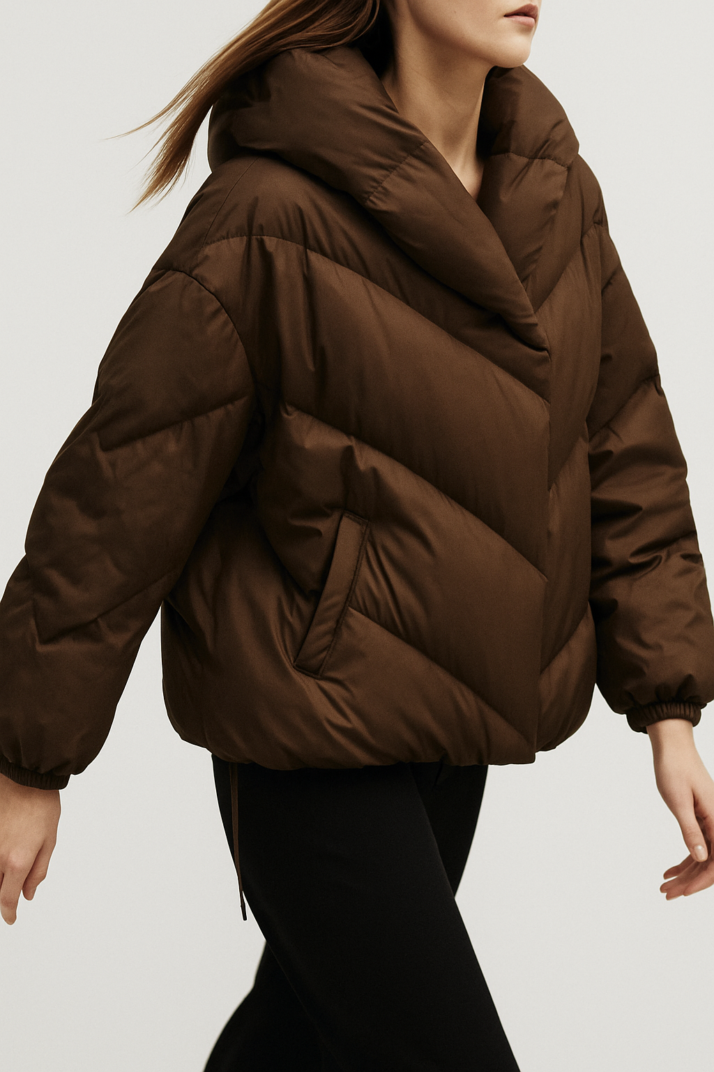 Woman wearing a hooded quilted puffer jacket in a cropped relaxed fit, styled with a light sweater and trousers._7